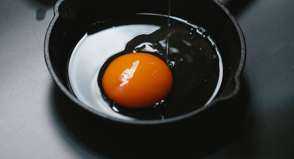 High angle of pan with uncooked egg on table prepared for making breakfast