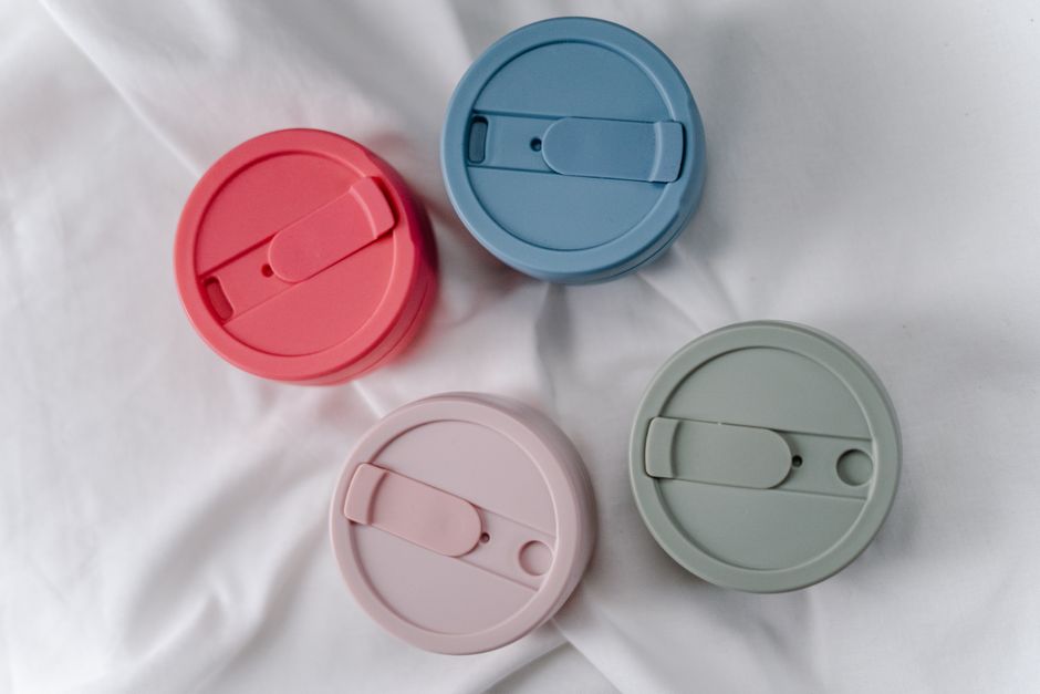 A close-up of four colorful, reusable silicone cup lids promoting zero waste.