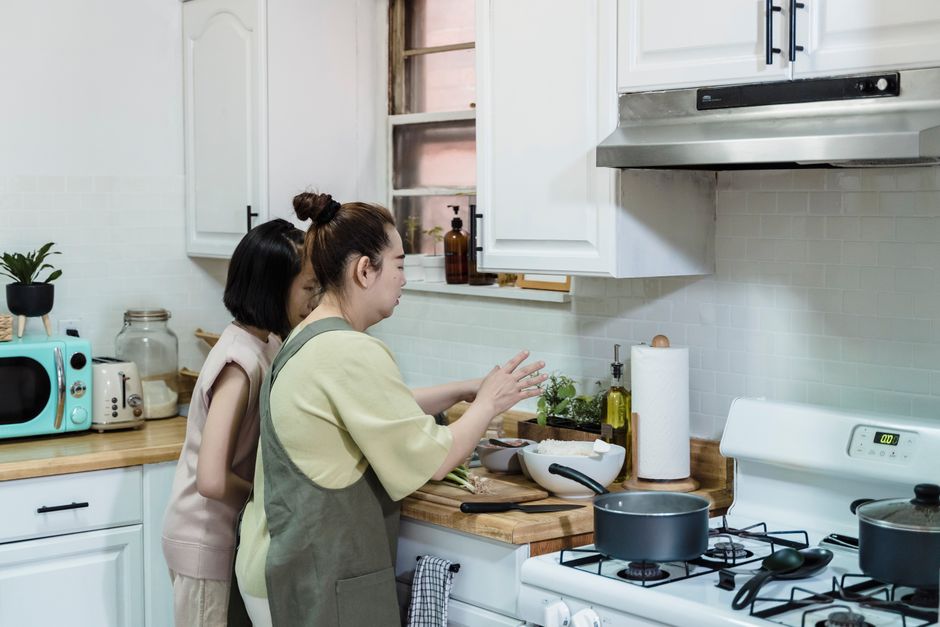 Asian mother and daughter preparing a meal in a modern home kitchen.